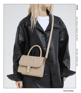 Detail of beige quilted shoulder bag featuring gold lock and FASHION emblem on a model