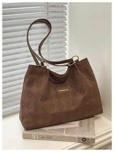 Detail of dark brown suede tote bag with diamond quilted texture and metal ring link