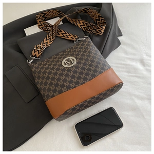 Detail of monogram crossbody bag featuring wide woven strap and metallic M logo