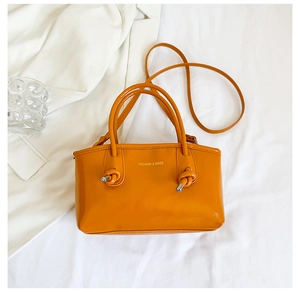 Top view of ginger yellow PU leather handbag with dual handles and metal knot details