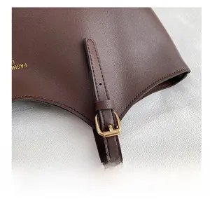 Détail du sac en cuir marron foncé avec boucle dorée et marquage de la marque