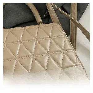 Gros plan détaillé de la texture matelassée géométrique et des coutures d'un sac beige