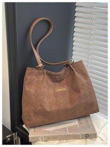 Detailed texture of brown quilted tote bag with Creative Cat label and gold rings