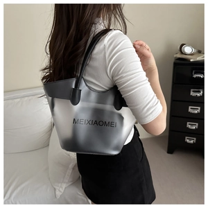 Close-up of semi-transparent grey PVC bucket bag with black leather trim and top handles