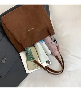 Détail d'un grand cabas en velours côtelé marron montrant un intérieur spacieux et objets