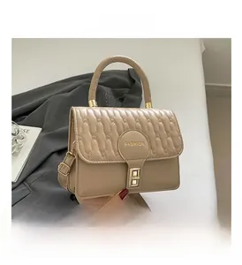 Close-up of quilted flap texture and gold FASHION lettering on a khaki handbag