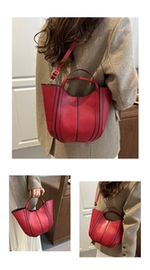 Detail view of red leather bucket bag with contrast stitching and versatile straps
