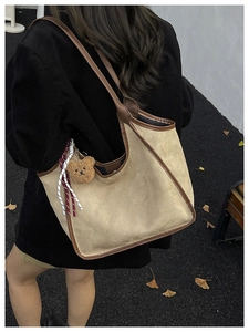 Outdoor shot of khaki corduroy bucket bag with brown leather trim and bear charm