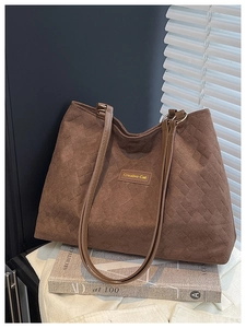 Detail of a brown quilted tote bag with Creative Cat label on a stylish background
