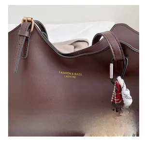 Détails du cabas vintage en cuir marron avec logo doré et pendentif d'ours doux