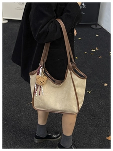 Chic beige suede bucket bag with brown leather trim and a cute teddy bear charm