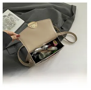 Détail de l'intérieur spacieux d'un sac bandoulière rétro beige avec des cosmétiques