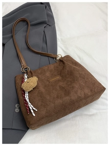 Macro detail of dark brown corduroy tote bag with diamond pattern and plush bear charm