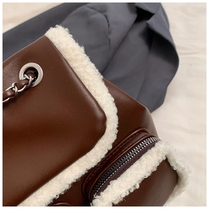Detail shot of brown leather and white faux fur trim with metal chain strap