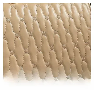 Close-up of beige leather handbag showing detailed oval quilted stitching and texture