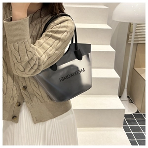 Detail of semi-transparent black bucket bag with logo print and leather trim design