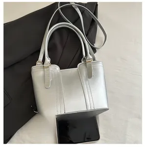 Detailed close-up of metallic silver bucket bag with gold hardware and vertical stitching