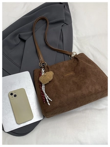 Detail of brown corduroy tote bag with diamond quilting and plush bear charm
