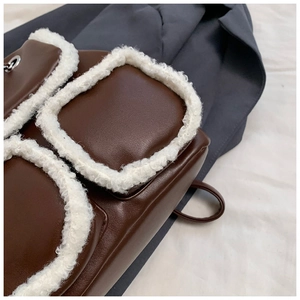 Close-up of brown leather tote bag featuring contrast white faux shearling fur trim detail