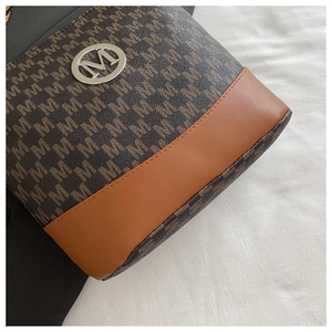 Detail of a brown patchwork crossbody bag with letter print and round silver metal M logo