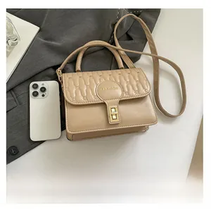Close-up of beige quilted crossbody bag with gold clasp and fashion logo detail