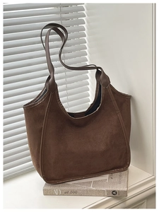 Minimalist brown suede bucket bag featuring high capacity and sleek shoulder strap detail
