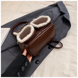 Detail view of brown PU leather backpack featuring white faux shearling pockets and chain strap