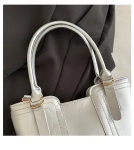 Detailed close-up of a silver handbag handle with gold rings and decorative stitching