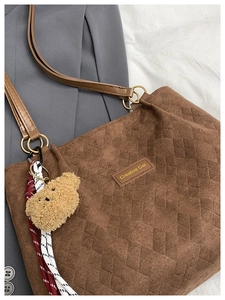 Detail of brown corduroy tote bag featuring quilted texture and creative cat leather tag