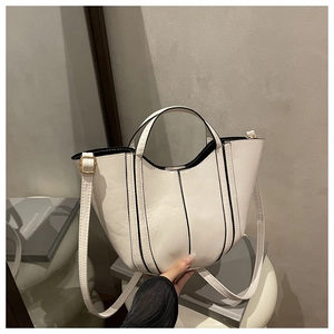 Close-up of white bucket bag with black contrast edges and golden hardware details
