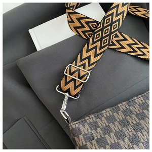 Close-up of stylish wide woven shoulder strap with metallic lobster clasp and M-letter print