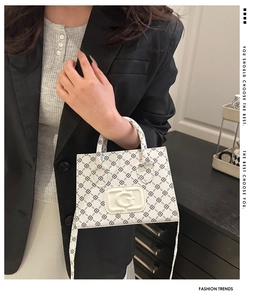 Detail of white cross-body bag with black geometric print and embossed G logo on model