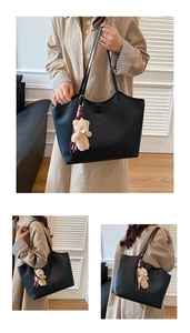 Détail du grand sac cabas en cuir noir avec lettres dorées et pendentif d'ours en peluche