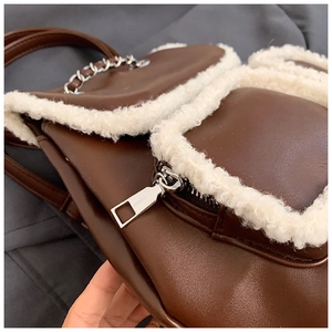 Detail of brown faux leather bag with white sherpa trim and silver metal chain