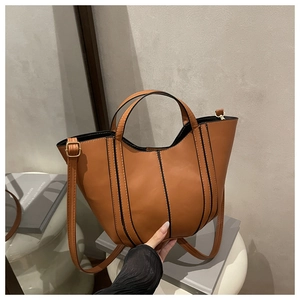 Detail of a brown tote bag with black contrast stitching and adjustable leather strap