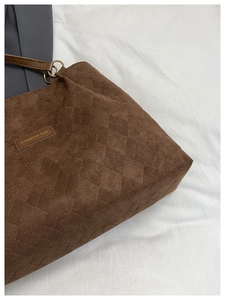 Detailed close-up of brown quilted corduroy tote bag showing stitching and logo patch
