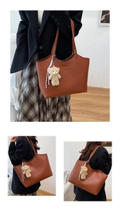 Détail du cabas en cuir marron foncé avec lettres dorées et pendentif d'ours mignon