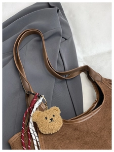 Detail of brown fuzzy bucket bag with cute bear charm and woven rope decoration