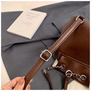 Detail of dark brown leather bag with silver chain drawstring and adjustable strap