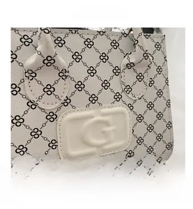 Close-up of white crossbody bag featuring black chain print and embossed logo plate