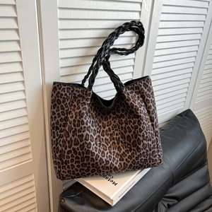 Leopard print tote bag with woven shoulder straps against a minimalist interior background