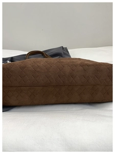 Detail of brown suede tote bag featuring quilted diamond texture and leather handle