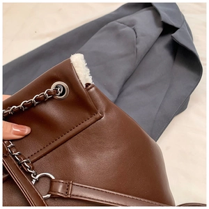 Detail of vintage brown leather handbag featuring white faux fur trim and silver chain