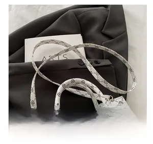Detail of adjustable gold-tone strap buckle on white clover pattern tote bag