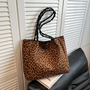 Spacious leopard print tote bag with woven handles on black leather sofa in home setting