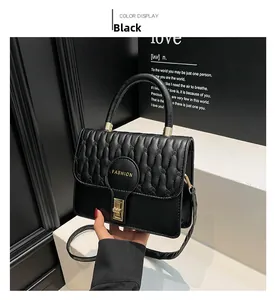 Detail of black V-quilted faux leather bag featuring golden metal twist lock and handle