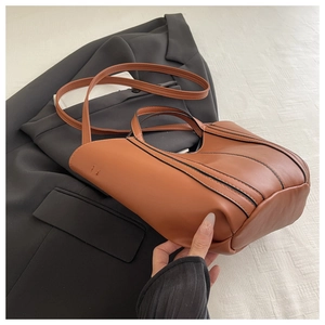 Chic caramel brown leather handbag with contrast black edging and soft pleated structure