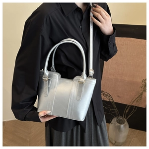 Detailed shot of silver metallic tote bag with vertical stitching and adjustable strap