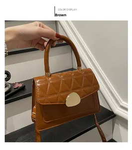 Détail du sac marron en cuir crocodile avec une élégante boucle en métal doré brillant