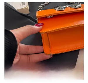 Detail of orange chain bag with silver bow buckle and precision stitching craft